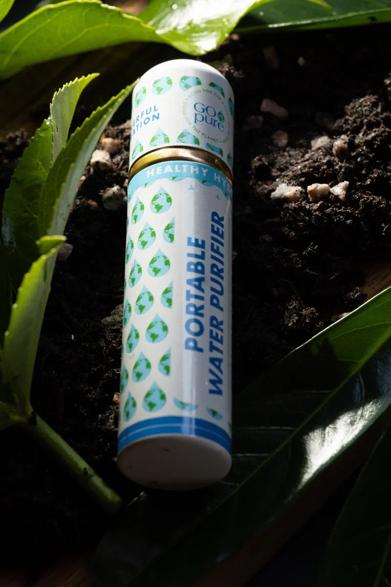 GOpure portable water purifier placed in soil with green leaves highlighting eco-friendly design.
