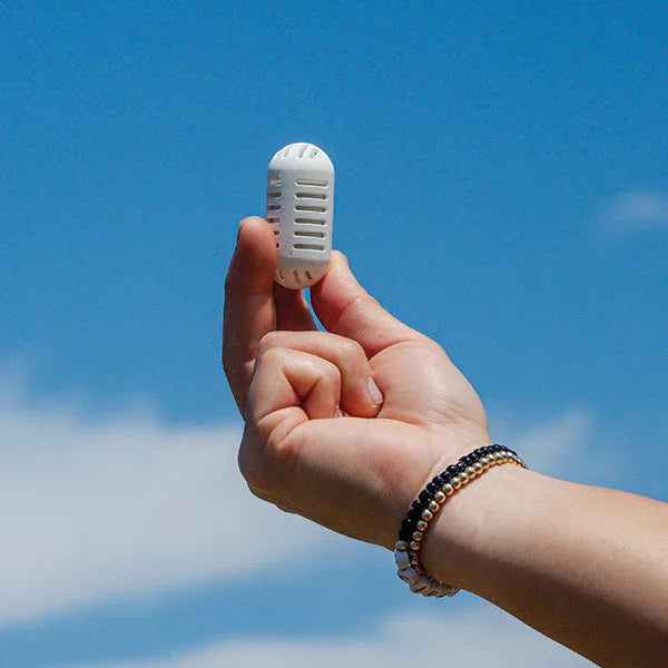 Hand holding GOpure water purifier pod against blue sky showing compact portable design.