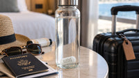 Filtered water bottle with GOpure Pod beside travel essentials and suitcase
